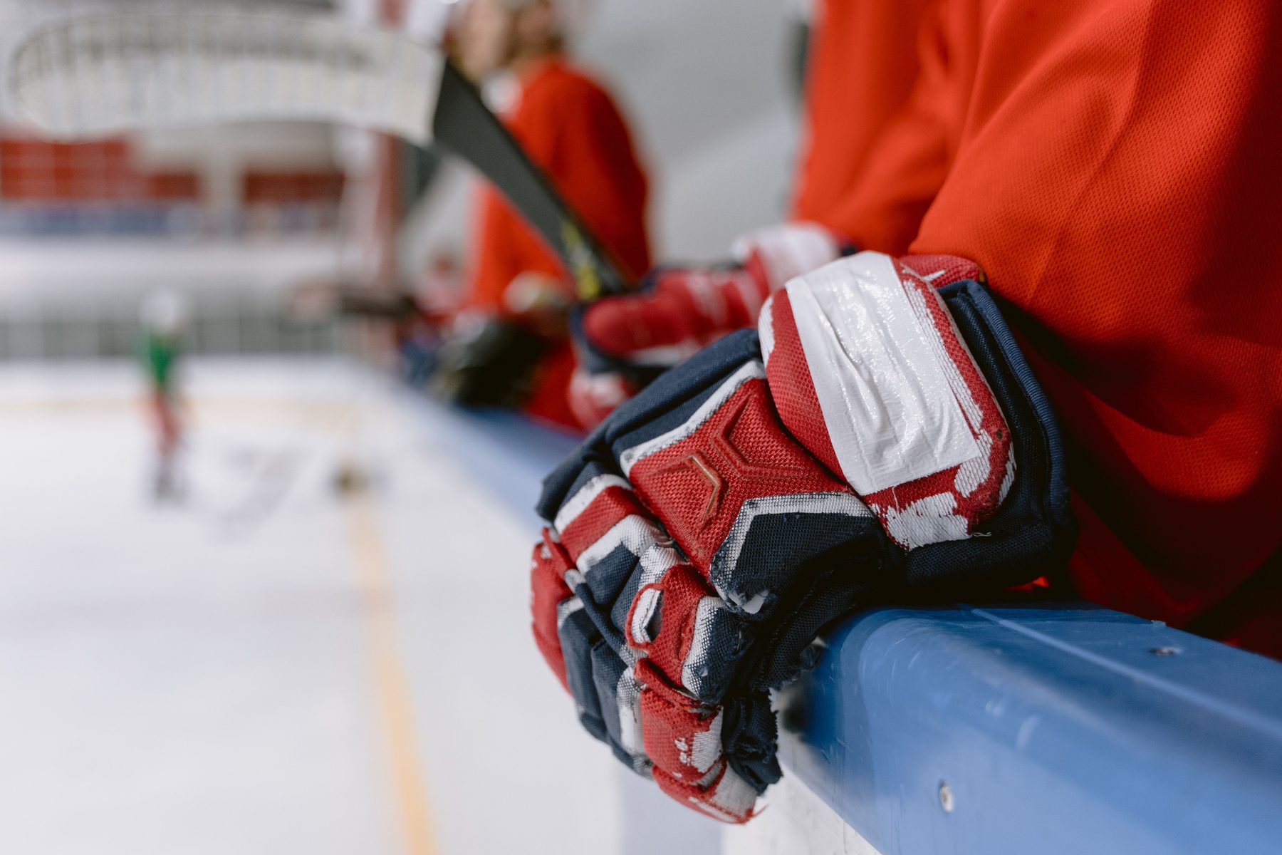 A player's taped gloves resting on the boards at the bench
