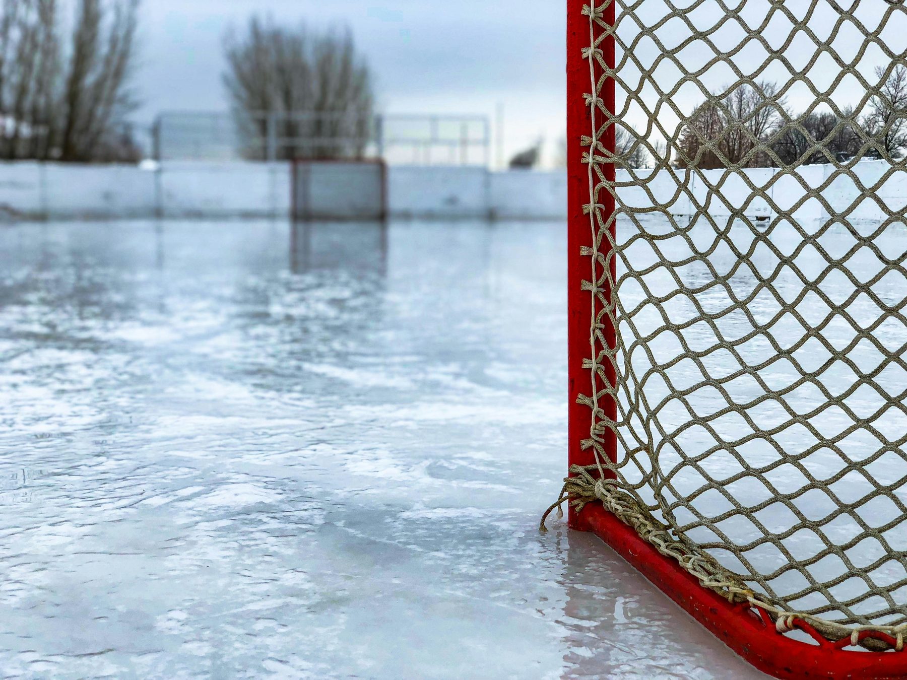 A hockey net on an outdoor sheet of ice on a grey winter afternoon